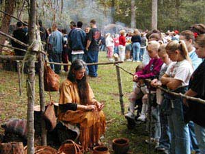 A person sits outside and weaves a basket